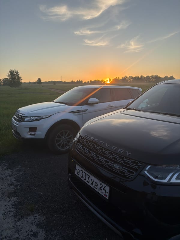 Two luxury SUVs parked in residential Krasnoyarsk during sunset