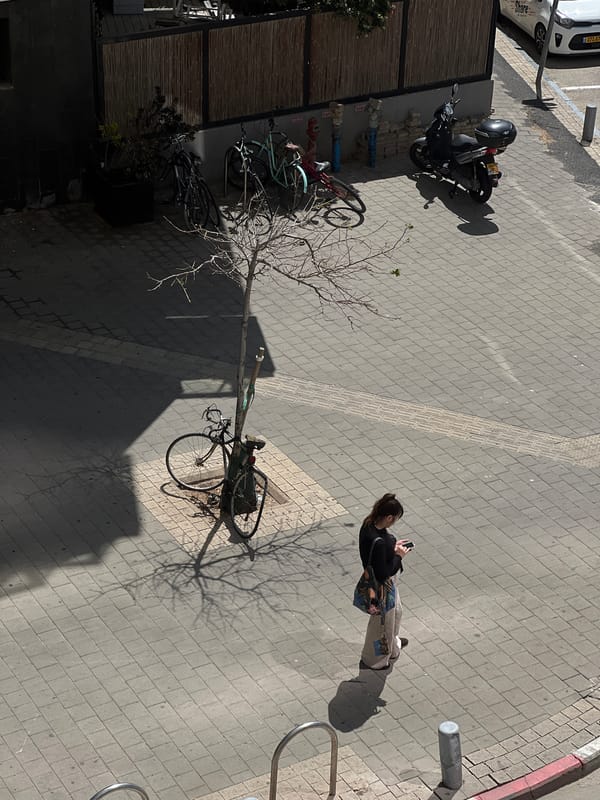 Woman checks phone on Tel Aviv sidewalk