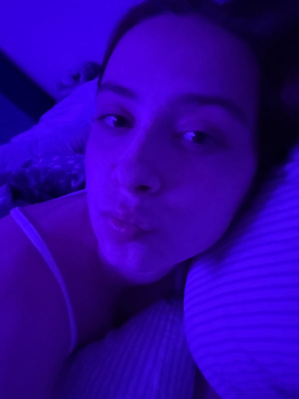 Young woman captures personal moments during bedroom photo session
