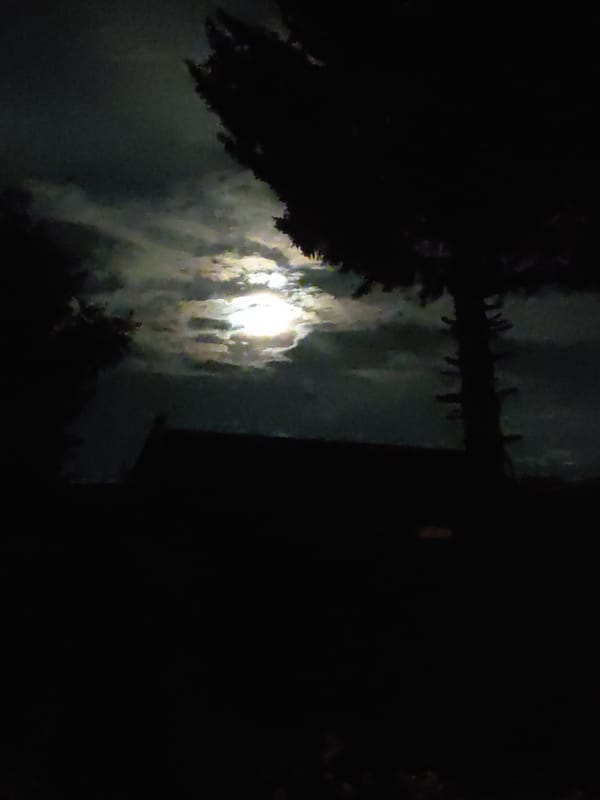 Full moon rising through clouds over Ridder, Kazakhstan