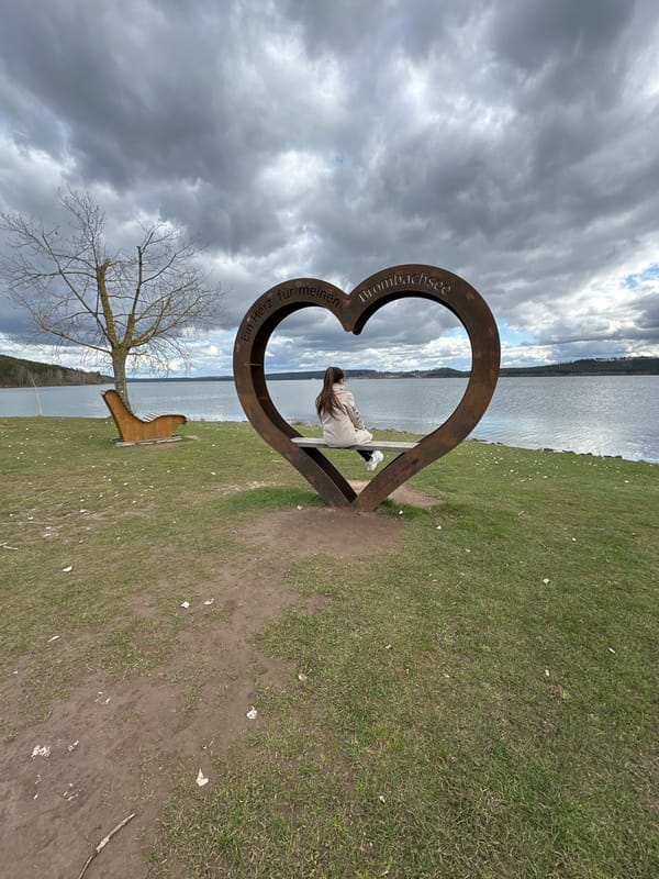 Woman sits on heart-shaped bench beside lake in Spalt