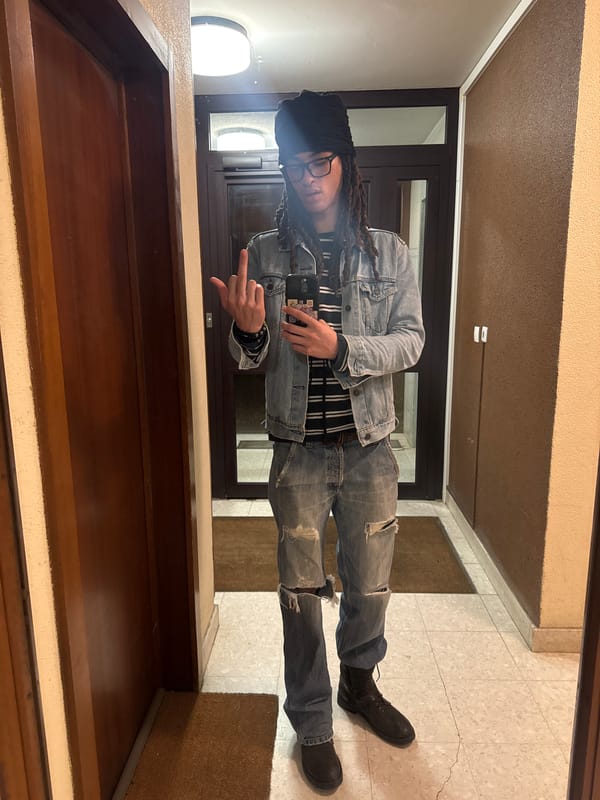Person makes obscene gesture while holding phone in hallway