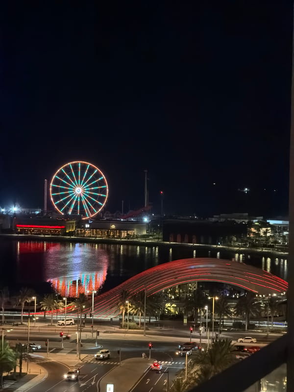 Lit-up Ferris wheel and waterfront skyline on a clear night