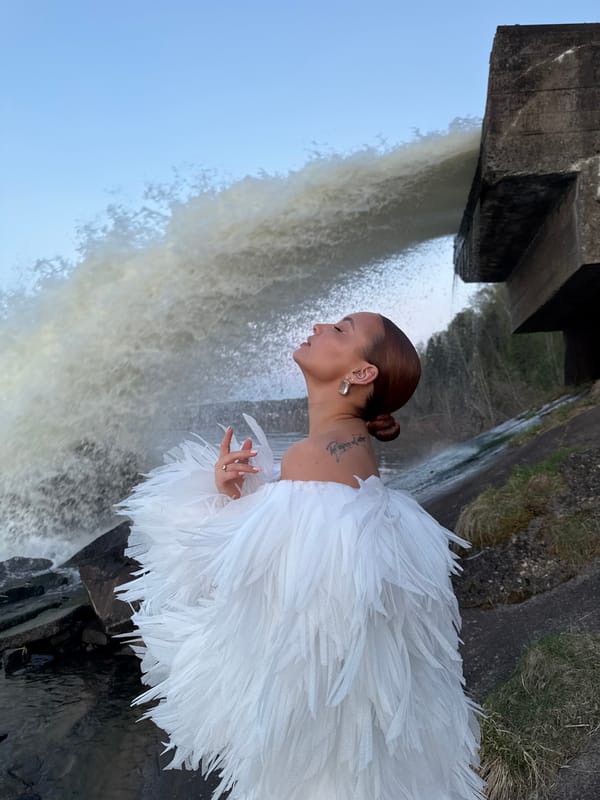 Woman poses near waterfall at dam site in Noviy, Russia
