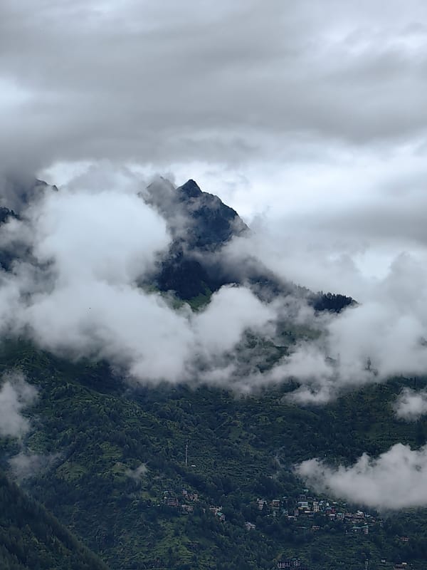 Misty morning over Vashisht's forested mountains and village