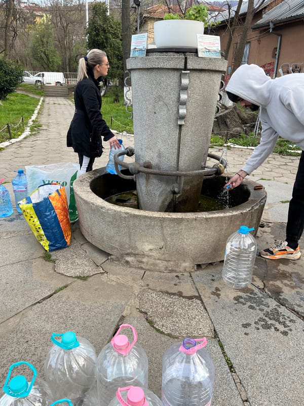 Two people fill water bottles at Sofia public fountain