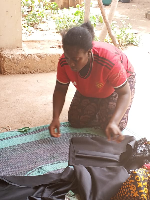Woman cuts black fabric outdoors on mat