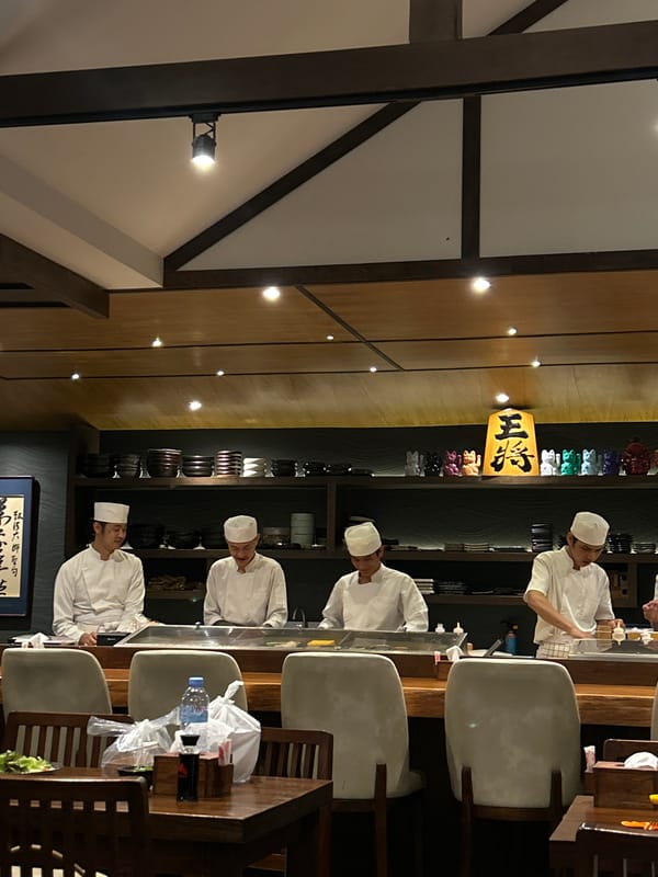 Family dines while chefs prepare sushi in Thailand restaurant