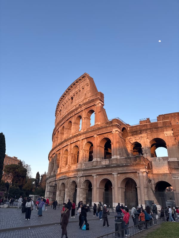 Moon visible over Rome's Colosseum under clear skies