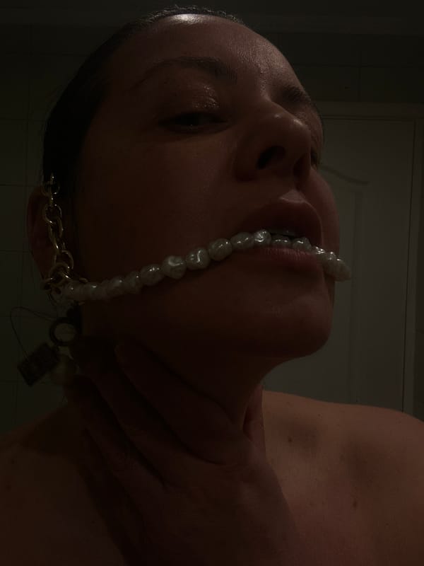 Person photographed wearing pearls across face in Riga