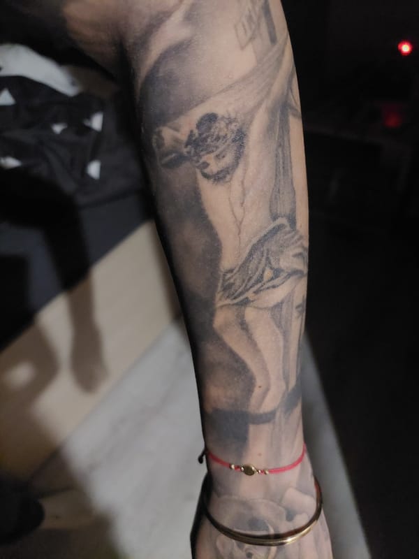 Tattooed individual photographed in Plovdiv showing religious and floral ink
