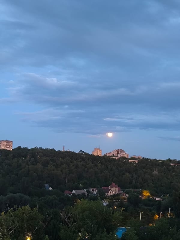 Chișinău at dusk: apartment blocks, storm clouds, and a rising moon