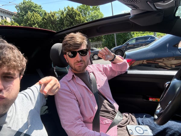 Two people photographed inside car during sunny afternoon in Milan