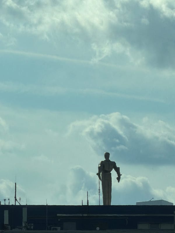 Suited statue silhouetted atop a Moscow industrial building
