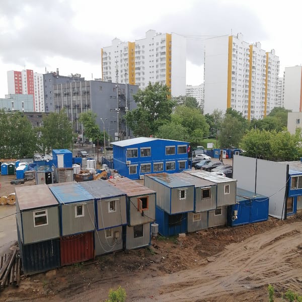 Urban construction site with stacked modular buildings observed