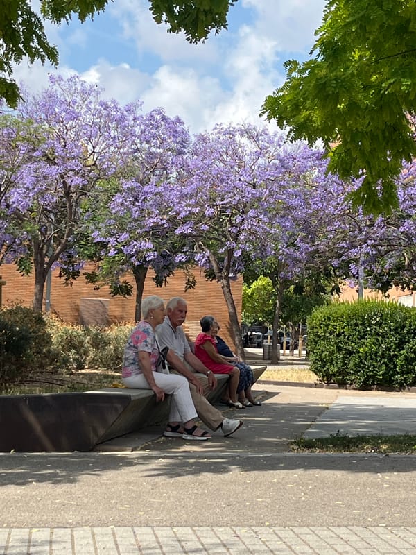 Three people sit on bench in Sant Boi park