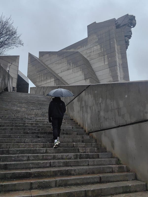 Umbrella walker navigates monument steps in rainy Shumen morning
