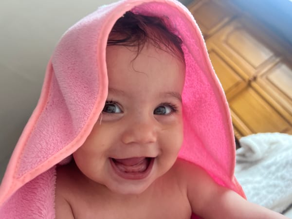 Baby in pink towel documented during meal time in Elena
