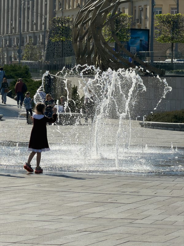 Girl in red dress interacts with water in Moscow