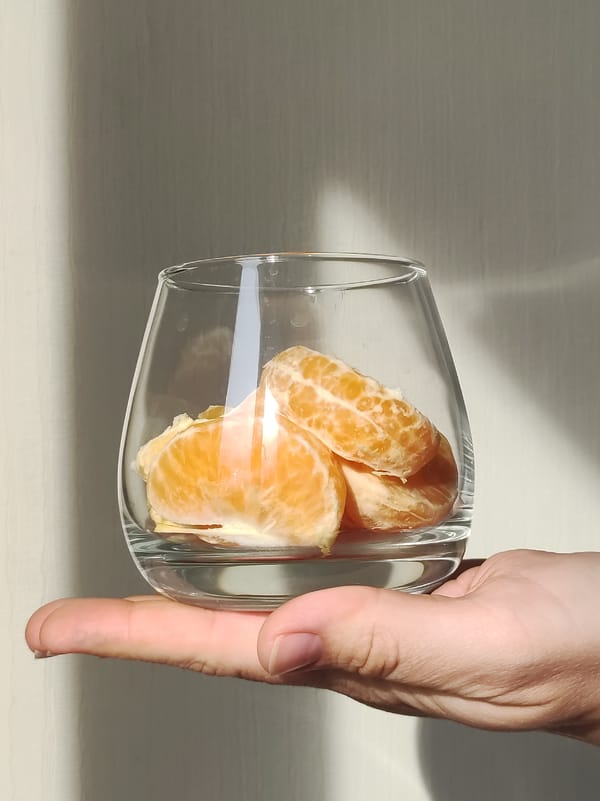 Woman prepares glass of orange segments indoors