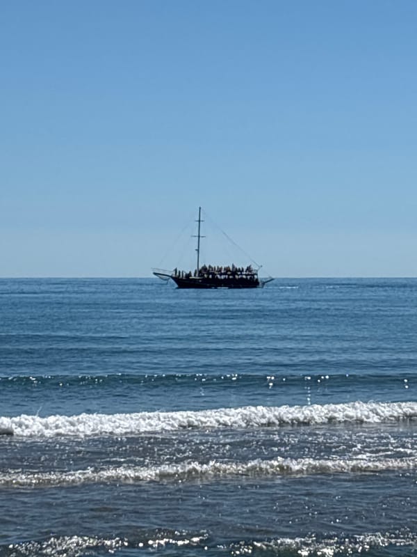 A sun-soaked beach day with boats, sand, and coastal views