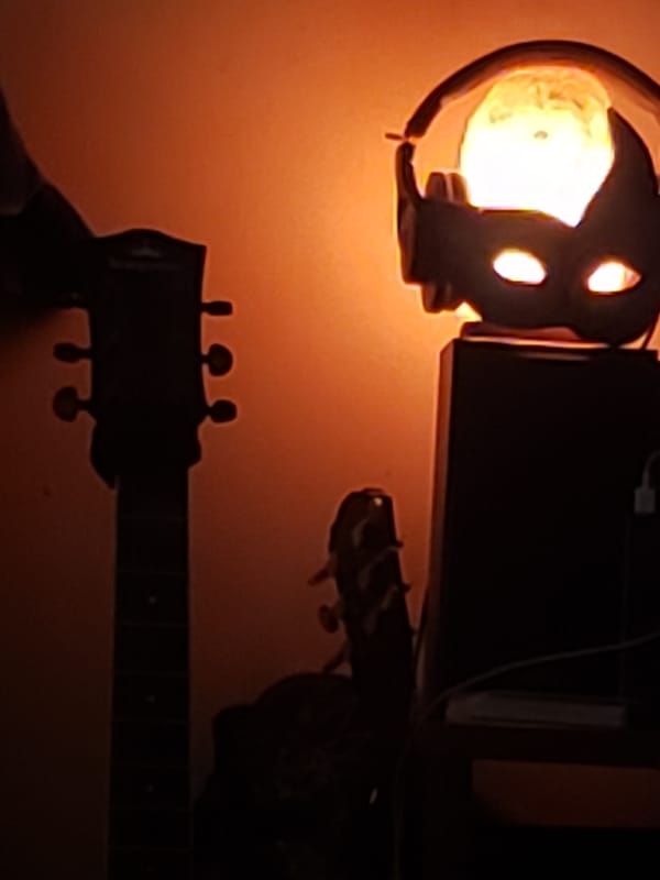 Acoustic guitar and lamp silhouetted against warm orange light