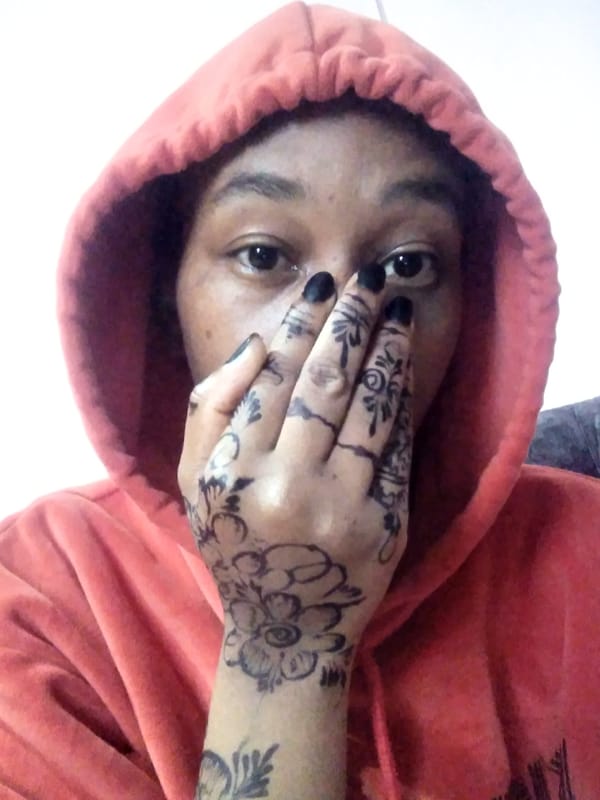 Person in orange hoodie with henna tattoos documented