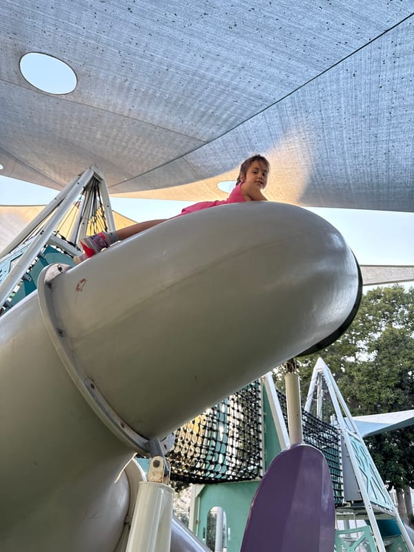 Girl in pink dress plays with doll around Netanya playground
