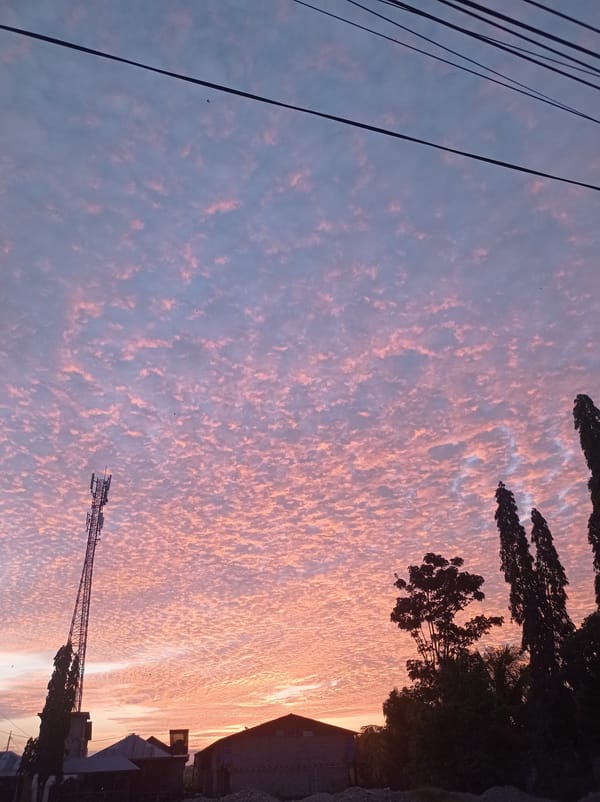 Pink sunset clouds over fields and rooftops in Gorontalo, Indonesia