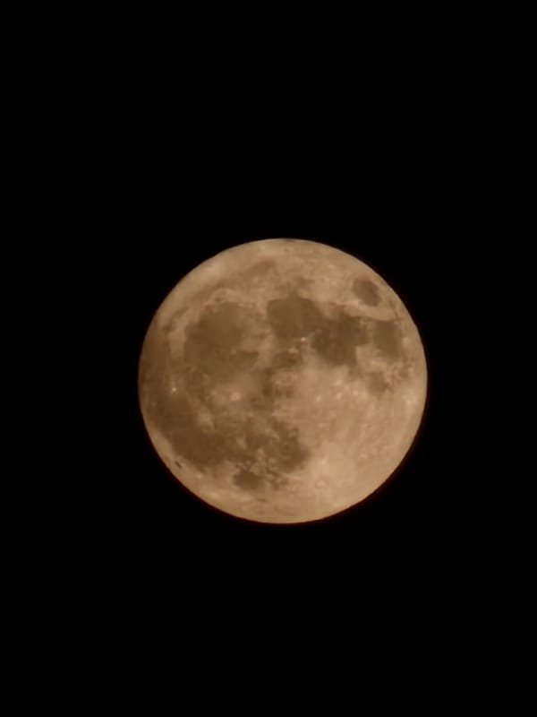 Brownish-orange full moon rises over Burgas, Bulgaria