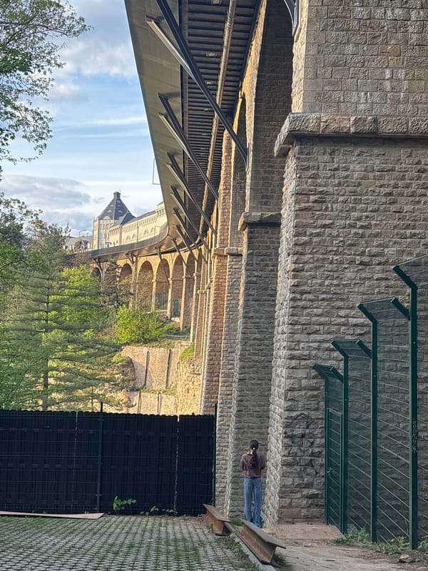 Woman stands beneath stone bridge in Luxembourg's Grund district