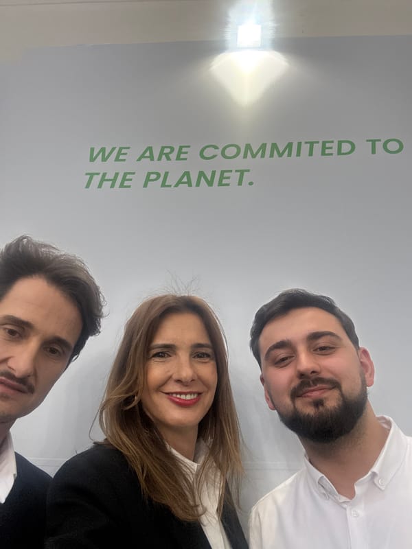 Three people take selfie at environmental message wall in Munich