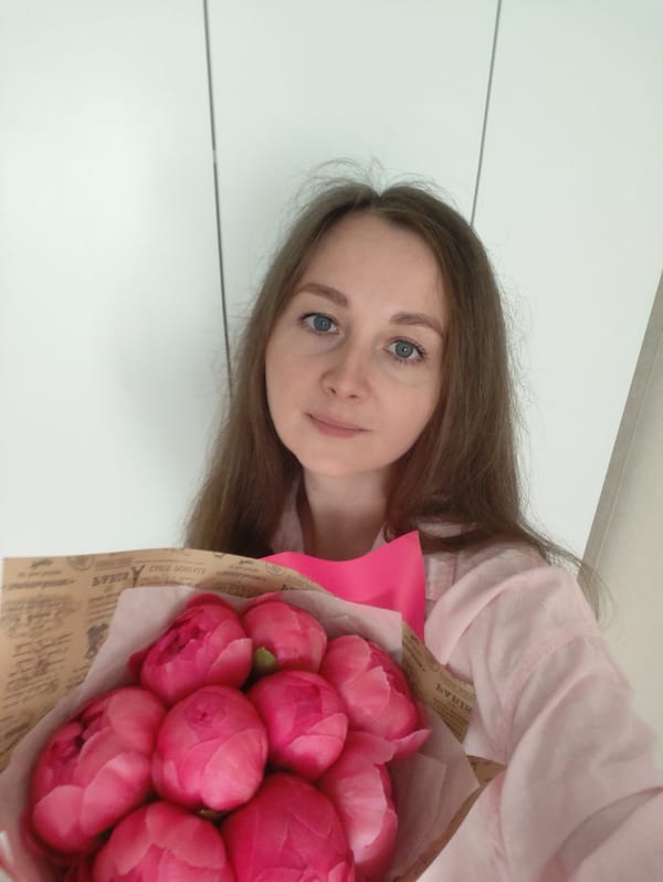 Woman poses with pink peonies in portrait session