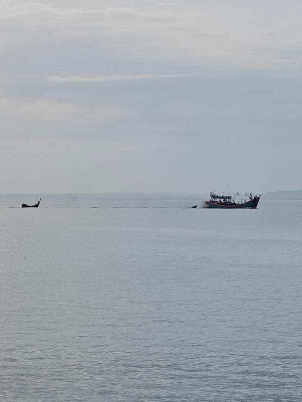Lhokseumawe waterfront at dusk: pier, fishing boats, and shoreline