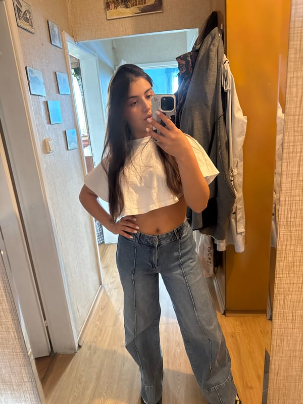 Young woman takes mirror selfie in casual outfit
