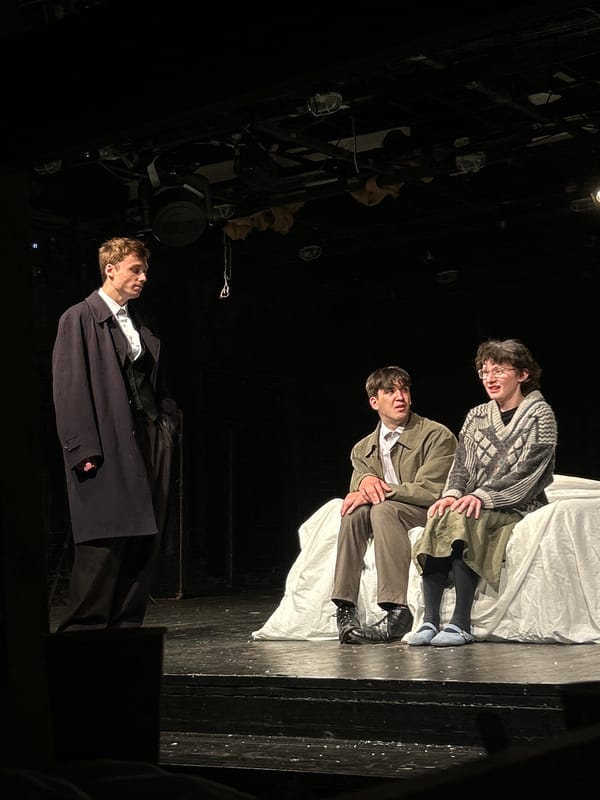 Stage performance with draped set and casual-dressed cast