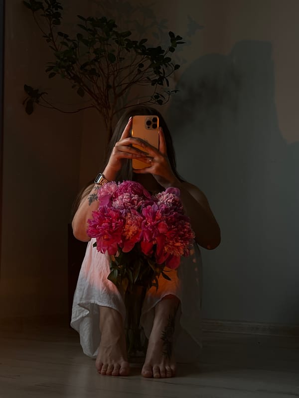 Woman takes selfies with pink peonies in Ternopil room