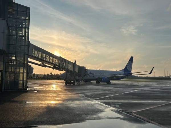 Wet tarmac and parked jets at Minsk Airport around dawn
