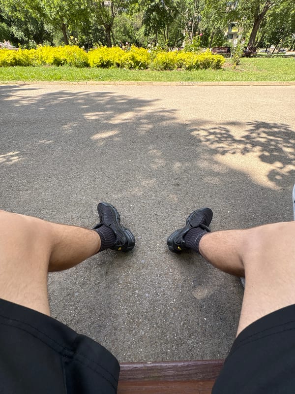 Person in athletic wear stands on pavement near greenery