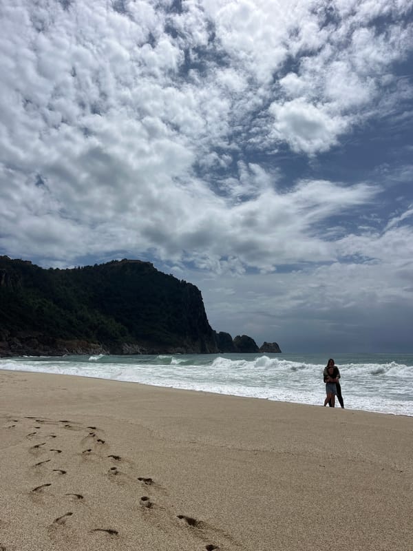 Two people stand at water's edge on Alanya beach