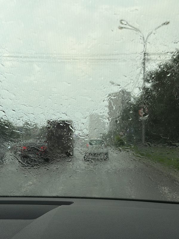 Rainy afternoon in a modern city, streets wet, clouds heavy