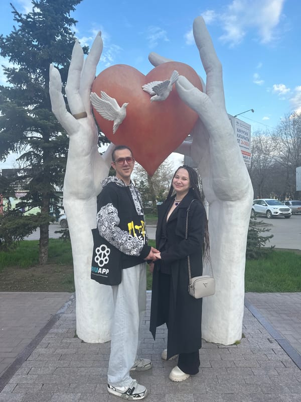 Couple photographs at heart sculpture monument in Engels, Russia