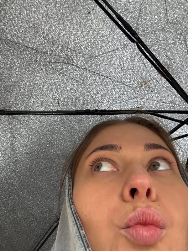 Woman shelters under umbrella during rainfall in Chernushka, Russia