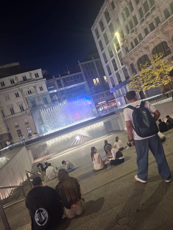 Evening crowd gathers at illuminated Milan water feature