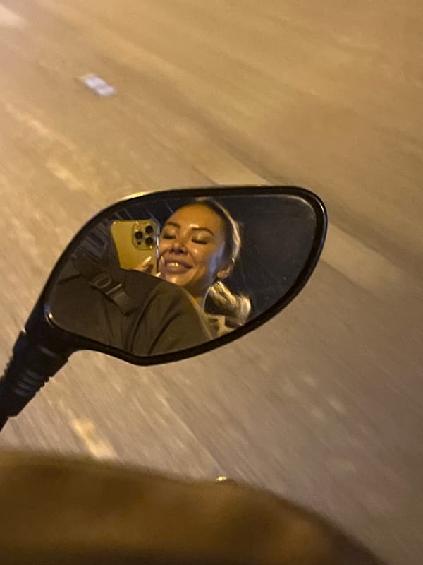 Person with smartphone captured in motorcycle mirror, Rawai Thailand