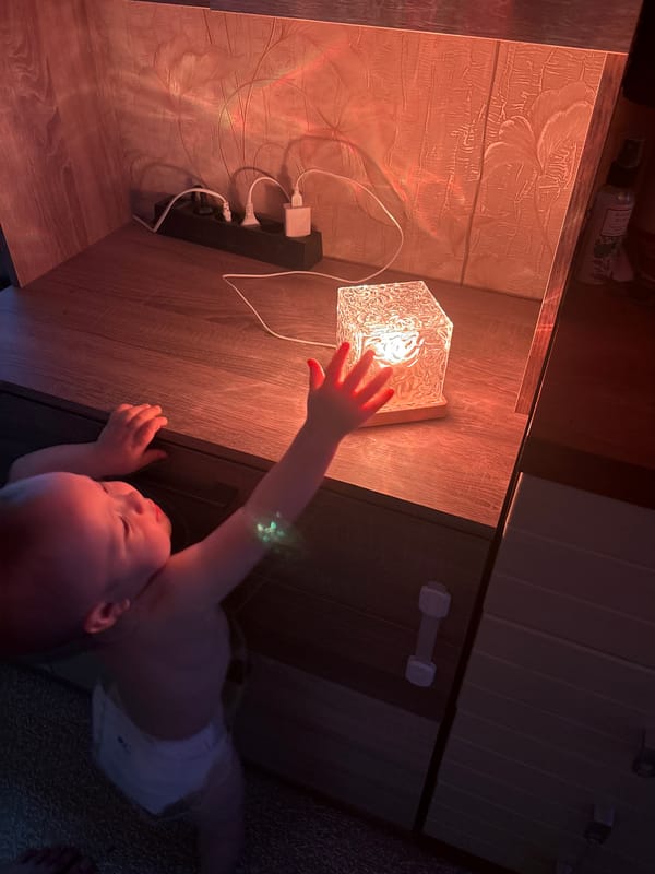 Baby plays with a glowing cube lamp at home
