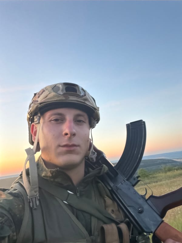 Military gear and AK-47 photographed outdoors at sunset