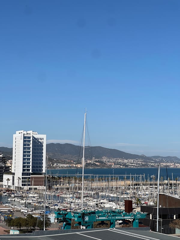 Sailboats moored at Badalona harbor with white building backdrop