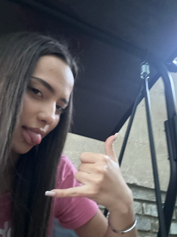 Person in pink shirt makes playful gestures, sticks tongue out