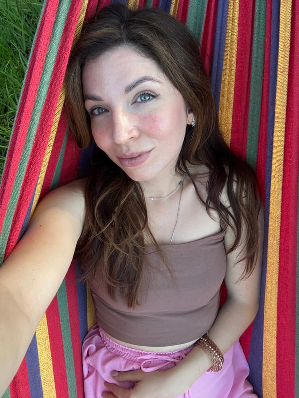 Woman relaxes in hammock under clear skies and trees